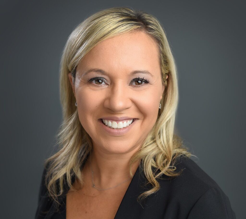 Professional headshot of a smiling woman with blonde hair, wearing a black outfit, looking confident and approachable - headshots Toronto.