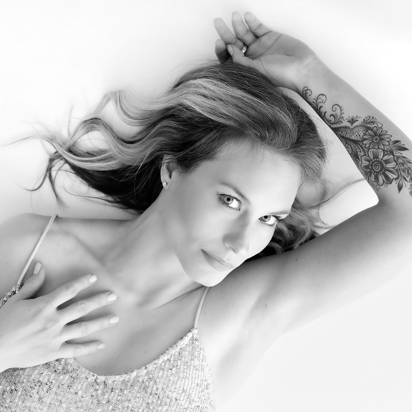 Toronto boudoir photography. Woman laying with sexy arm tattoo