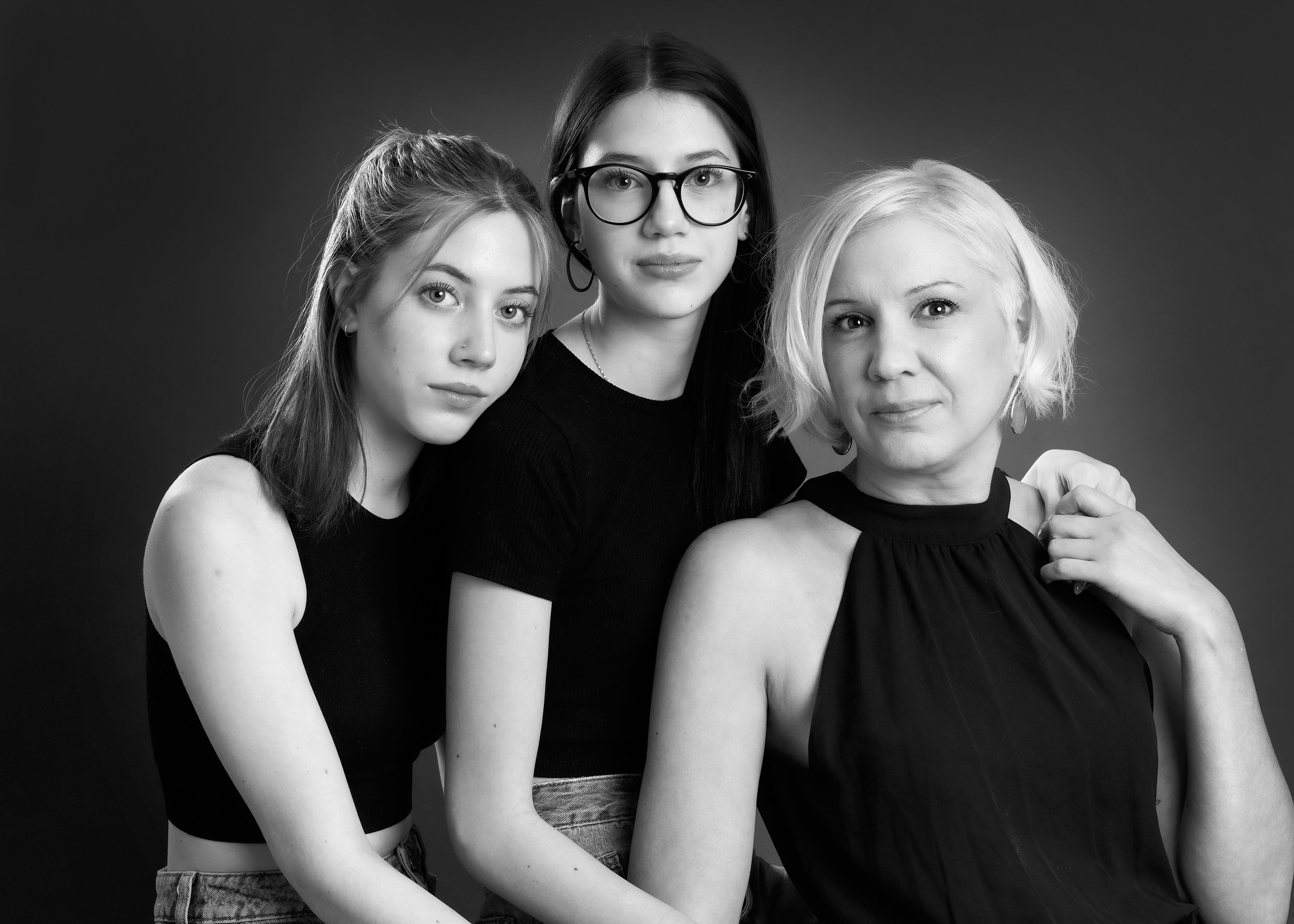 A mother and her two teenage daughters posing together for a photoshoot