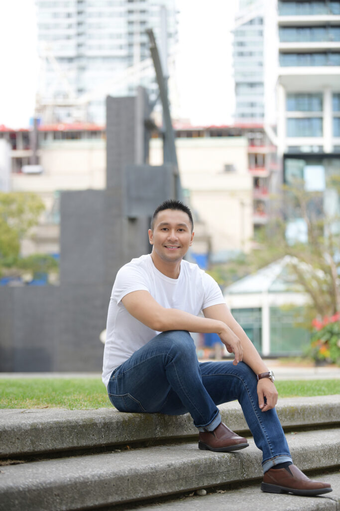 Young man sitting and smiling at the camera with a city skyline backdrop, showing a modern urban lifestyle