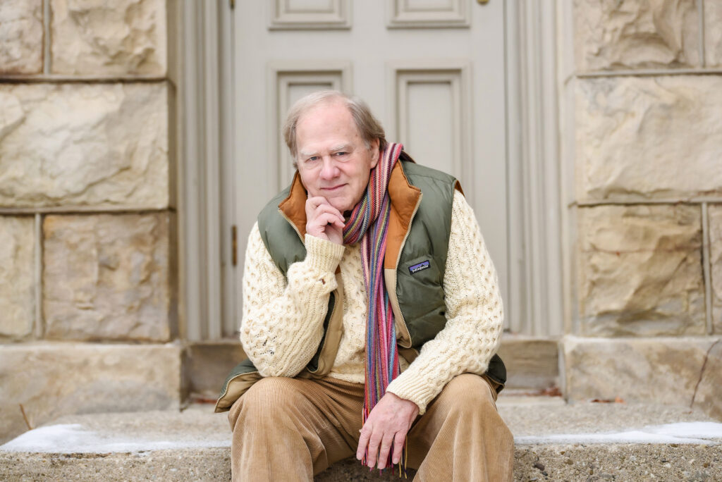 Mature man in casual wear sitting on steps smiling at camera
