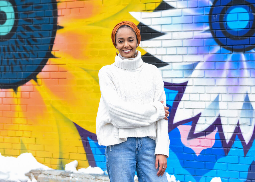 Stylish individual posing in front of a vibrant street mural, showcasing personality in a Hinge profile photo