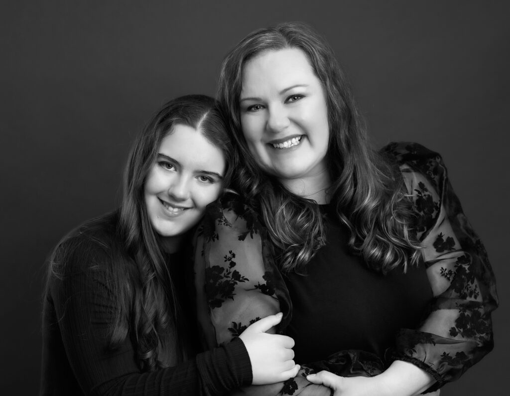 A mother and daughter embracing and smiling during their photoshoot.