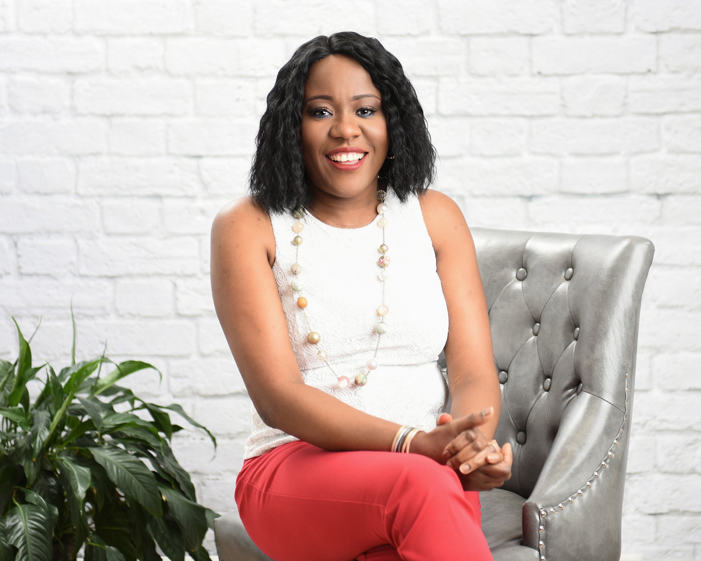 corporate photographers Smiling woman in a white blouse sitting against a light, textured background.