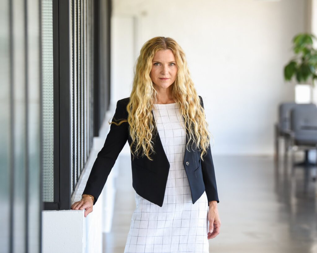 Professional woman in business attire standing confidently in a modern office setting.