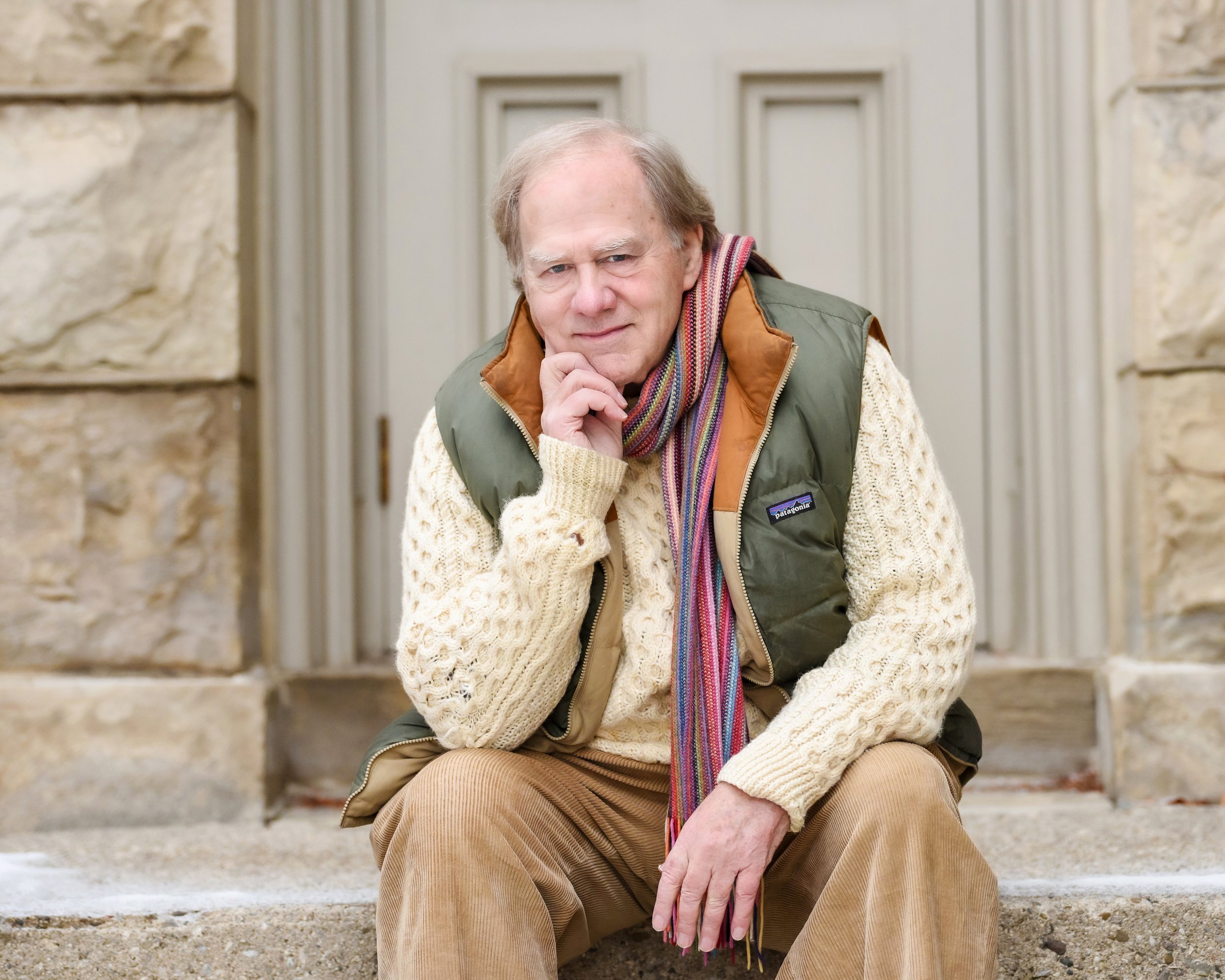 Older man in warm clothing sitting on steps outside a building. Captured by Ellahrika corporate photographers