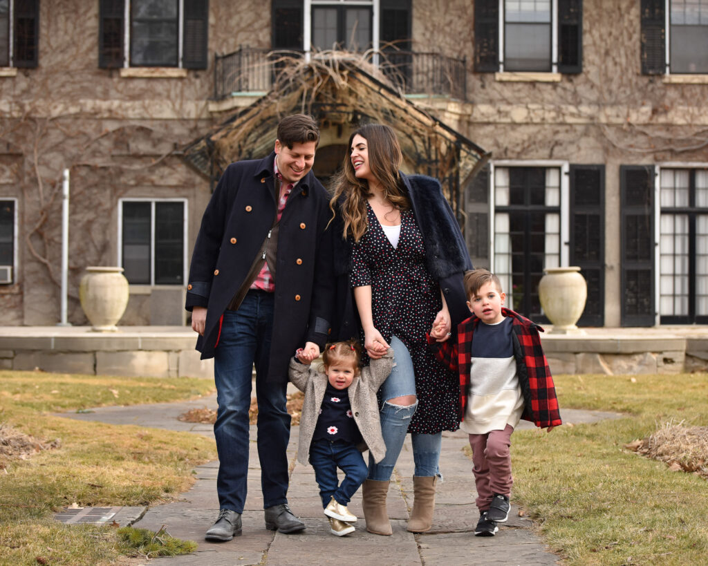 A family walking together in front of a historic home, showcasing the best family photographers near me capturing candid moments.