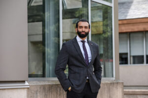 Young man standing professionally outdoors by an office building.