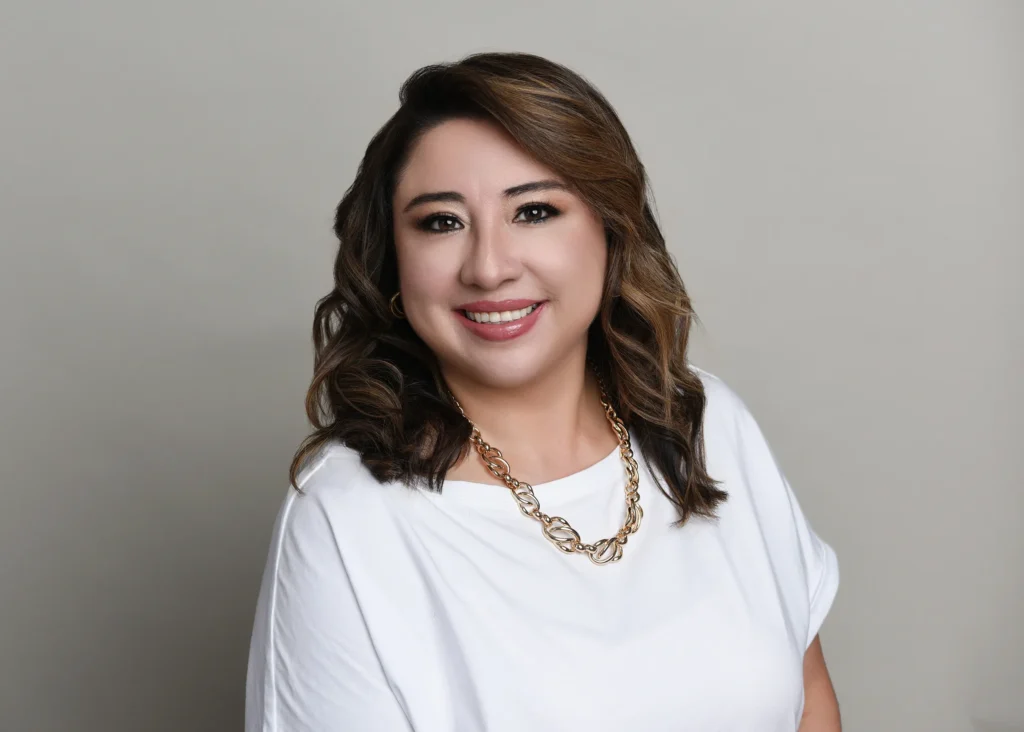  Professional female counselor with wavy hair and a white blouse smiling confidently.