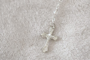 Close-up of a silver cross on a soft textured fabric, used for a baptism ceremony.