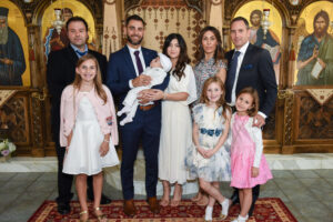 Baby being held and supported by family members during a family portrait during baptism ceremony in a church.