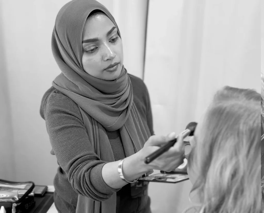 A makeup artist applying eyeshadow on a client, demonstrating the makeup process as part of how to prepare for a photoshoot.