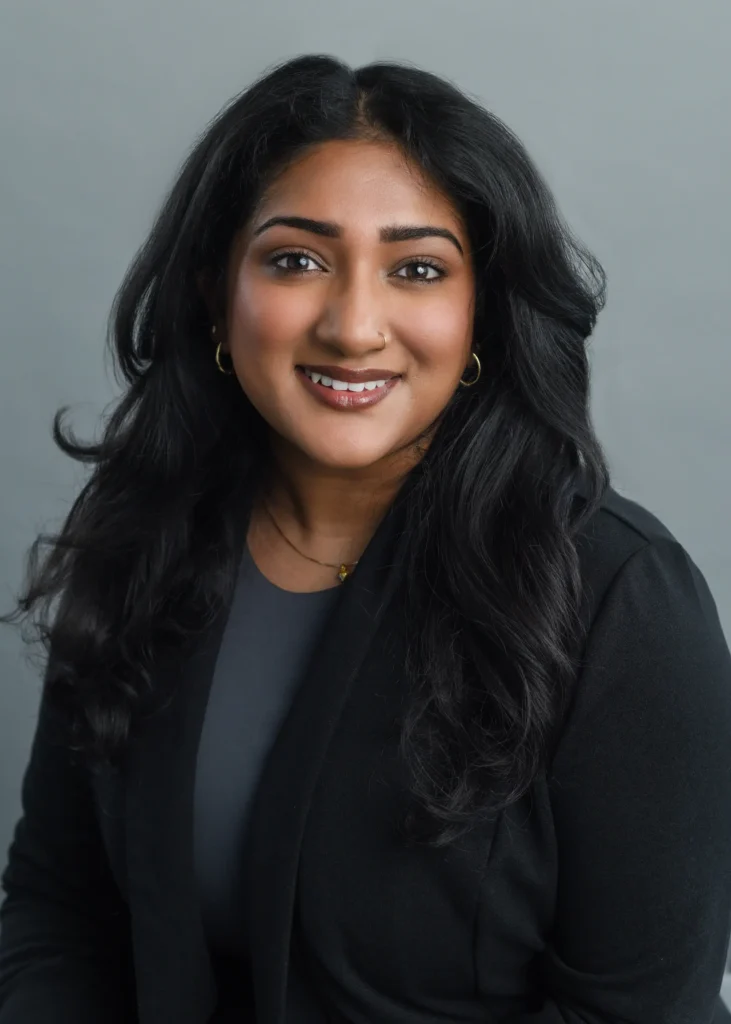 Professional corporate headshot of a woman in a black blazer with a confident smile