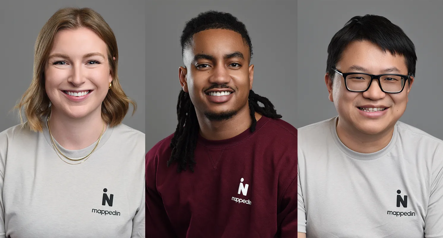 Three diverse team members in corporate headshots, each wearing branded 'Mappedin' shirts with a neutral gray background, displaying consistent professionalism and unity