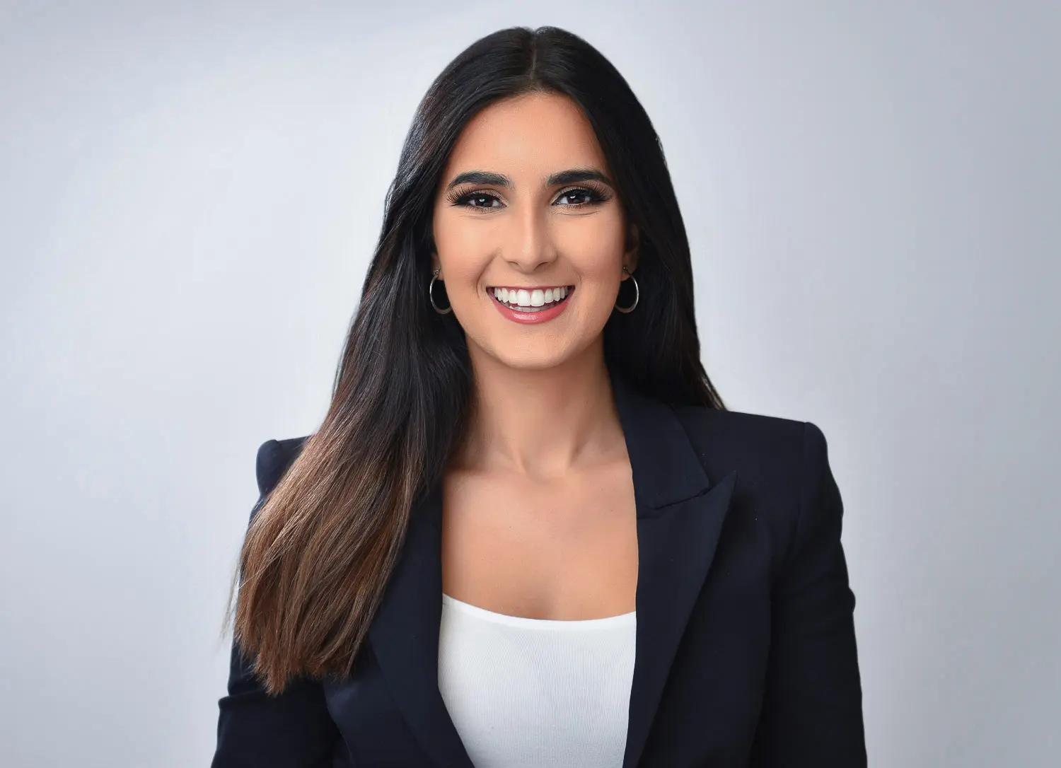 Professional corporate headshot of a woman in a black blazer with a confident smile.